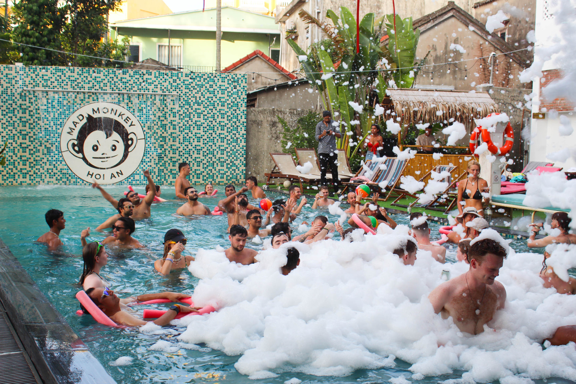 Travellers at a tropical hostel pool party at sunset